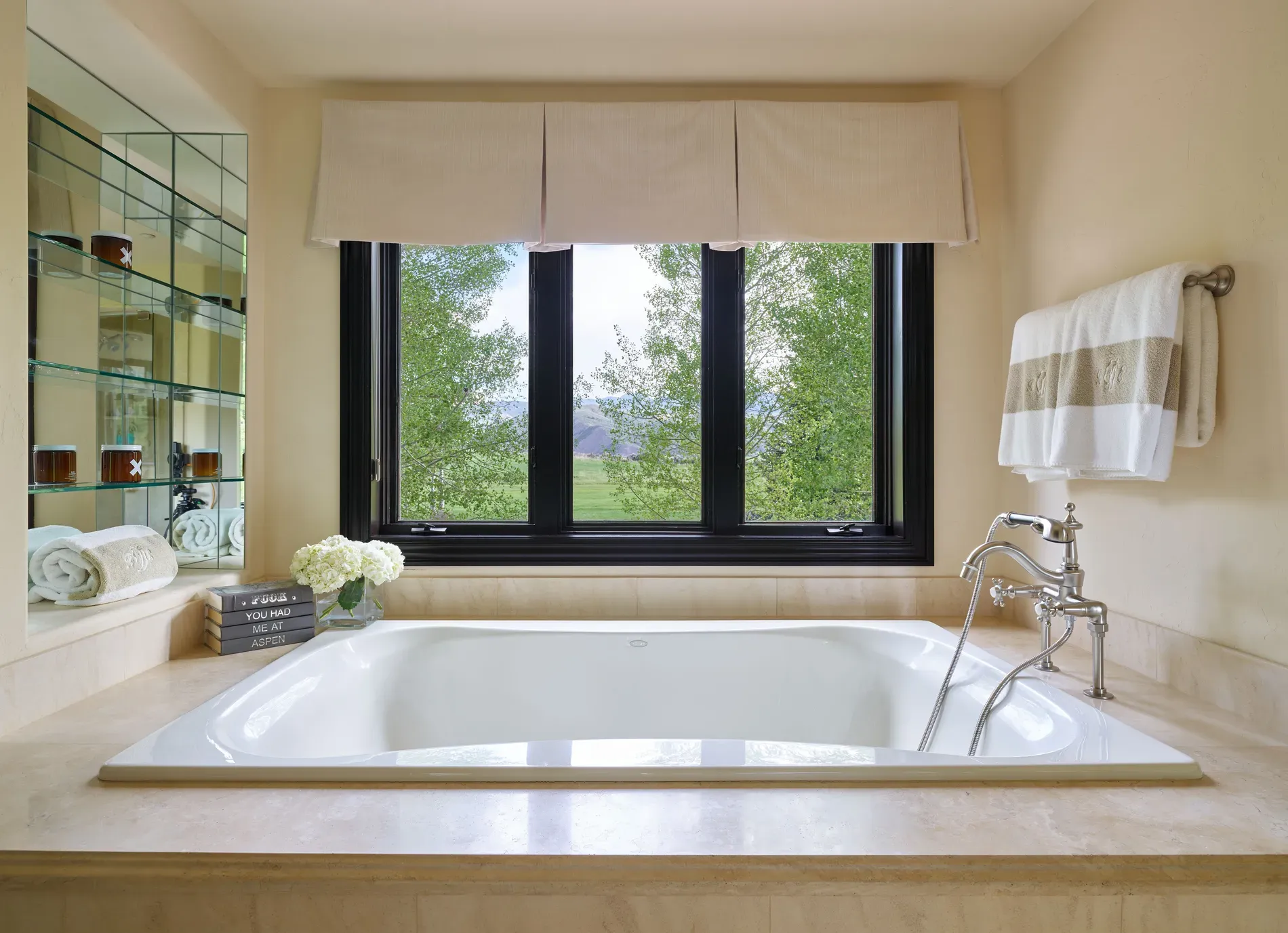 Serene bath with an oval soaker and beige stone. Spa-ish without fuss.