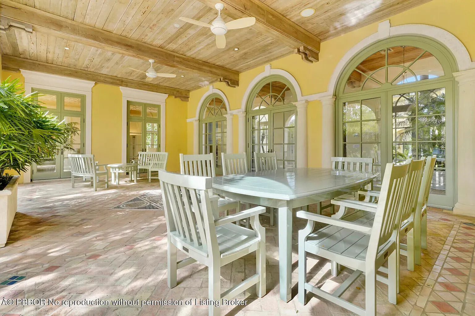 Sunroom goes soft yellow and sage. From this angle, arched windows flood everything.