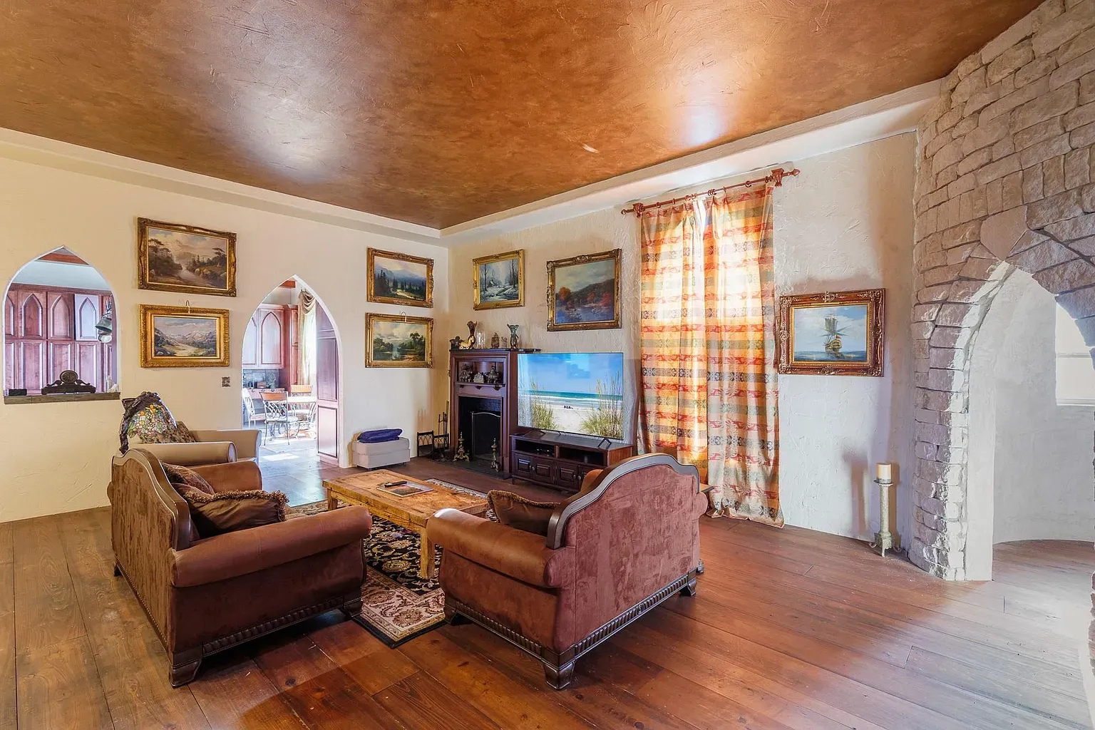 Living room leans cozy. Dark floors, soft walls, a little artsy layered.