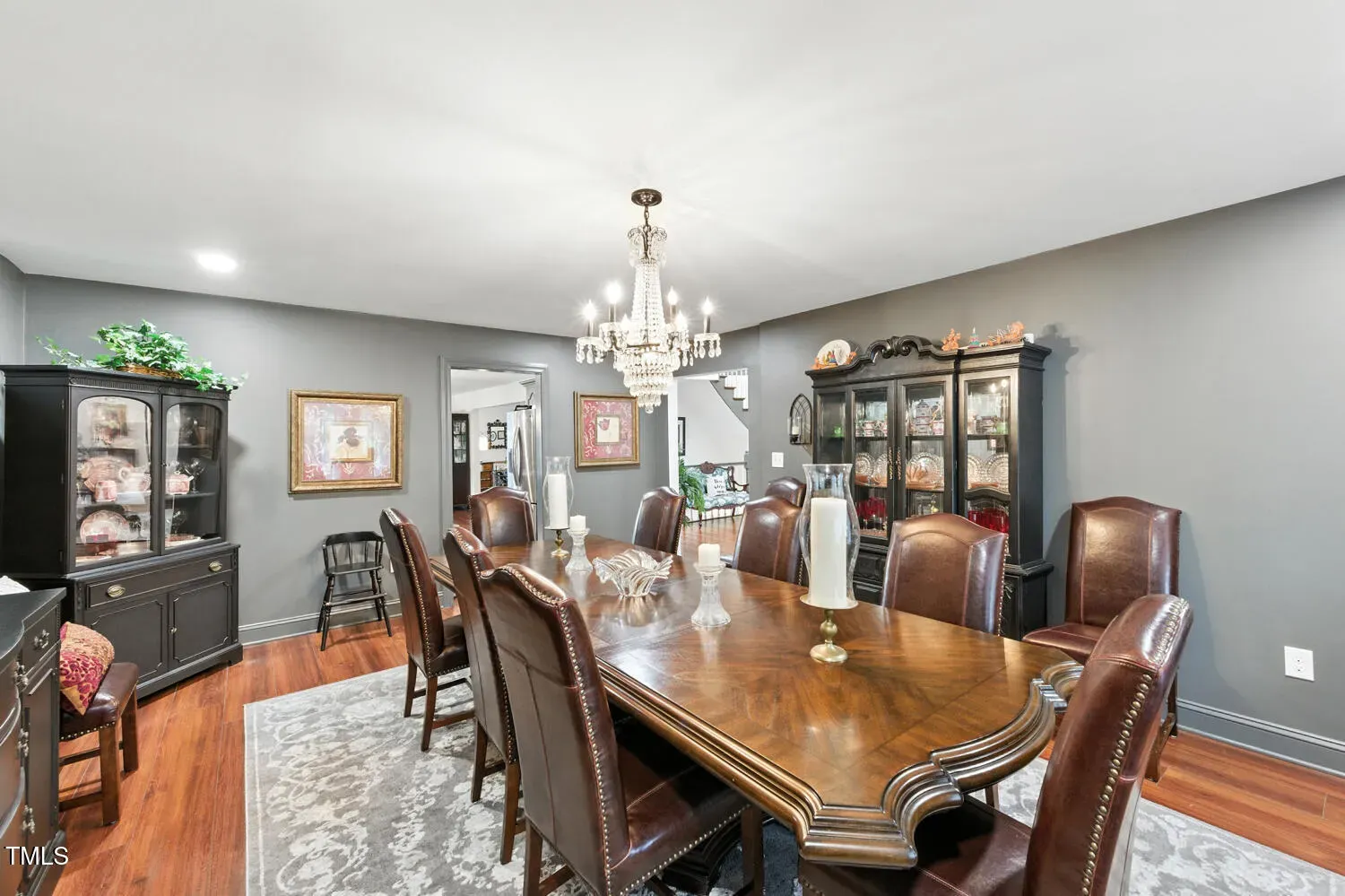 Dining room flex. long polished table, dark chairs, statement chandelier. Host mode.