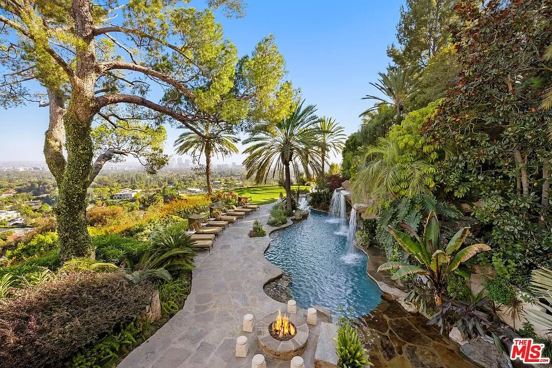 From this angle, backyard pool curves a river—stone edges, palms everywhere.