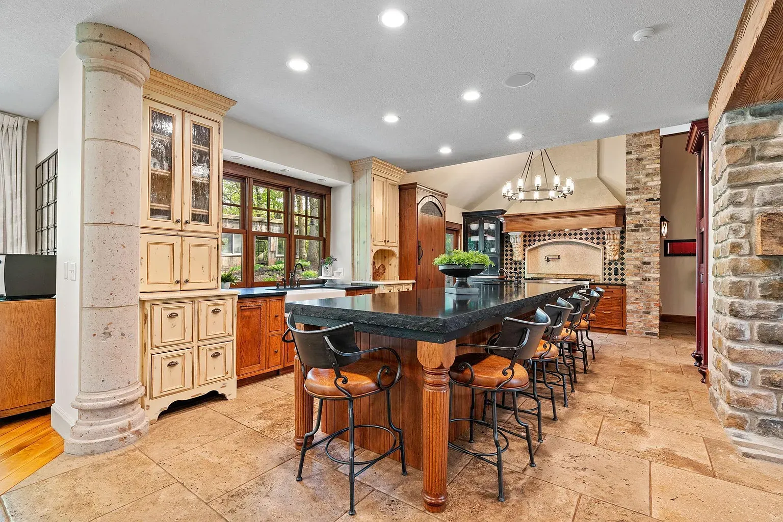 Big granite island, honey cabinets, black stools. Feels warm without trying.