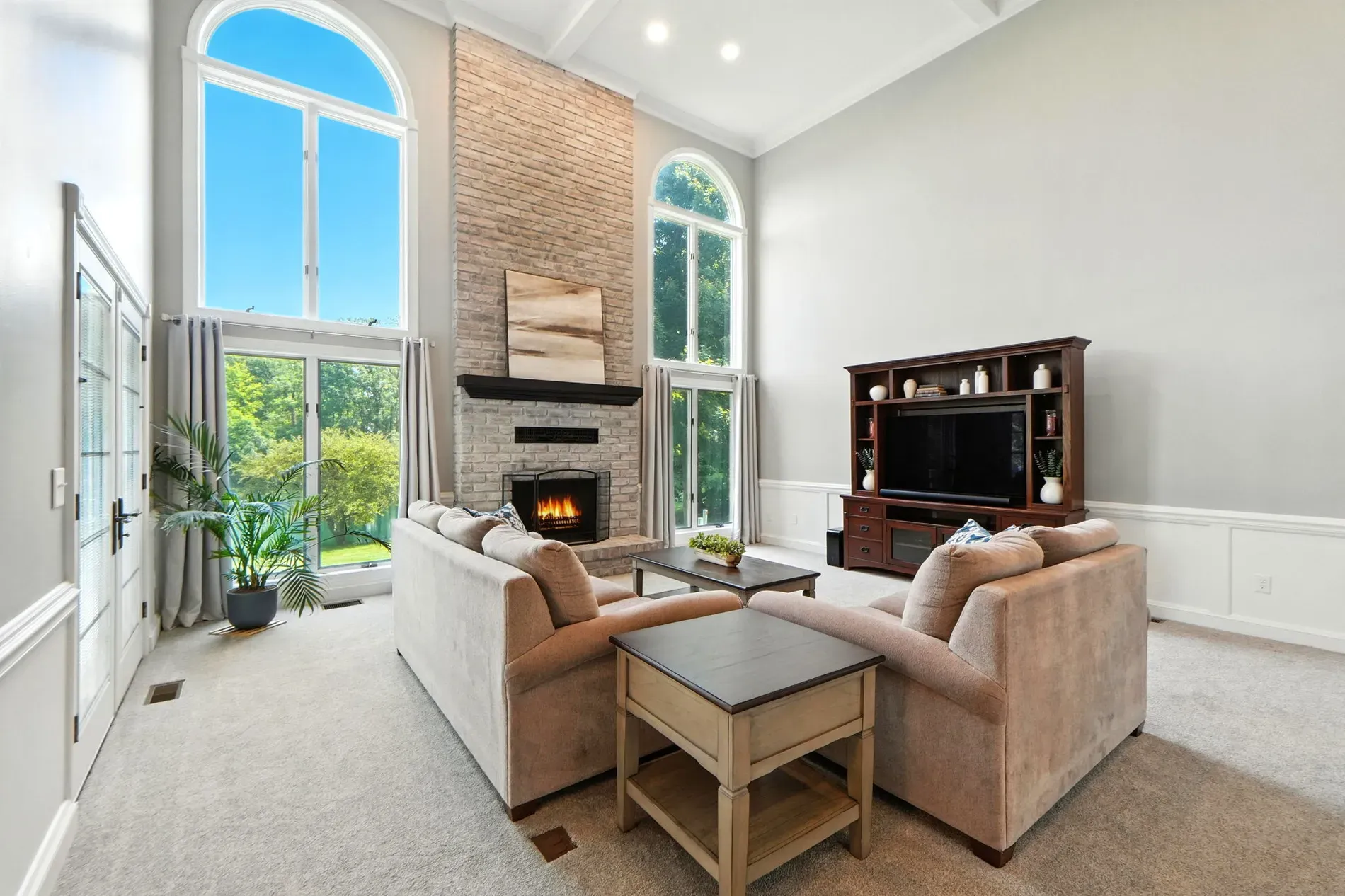 Two-story living room with arched windows. That stone fireplace goes hard.