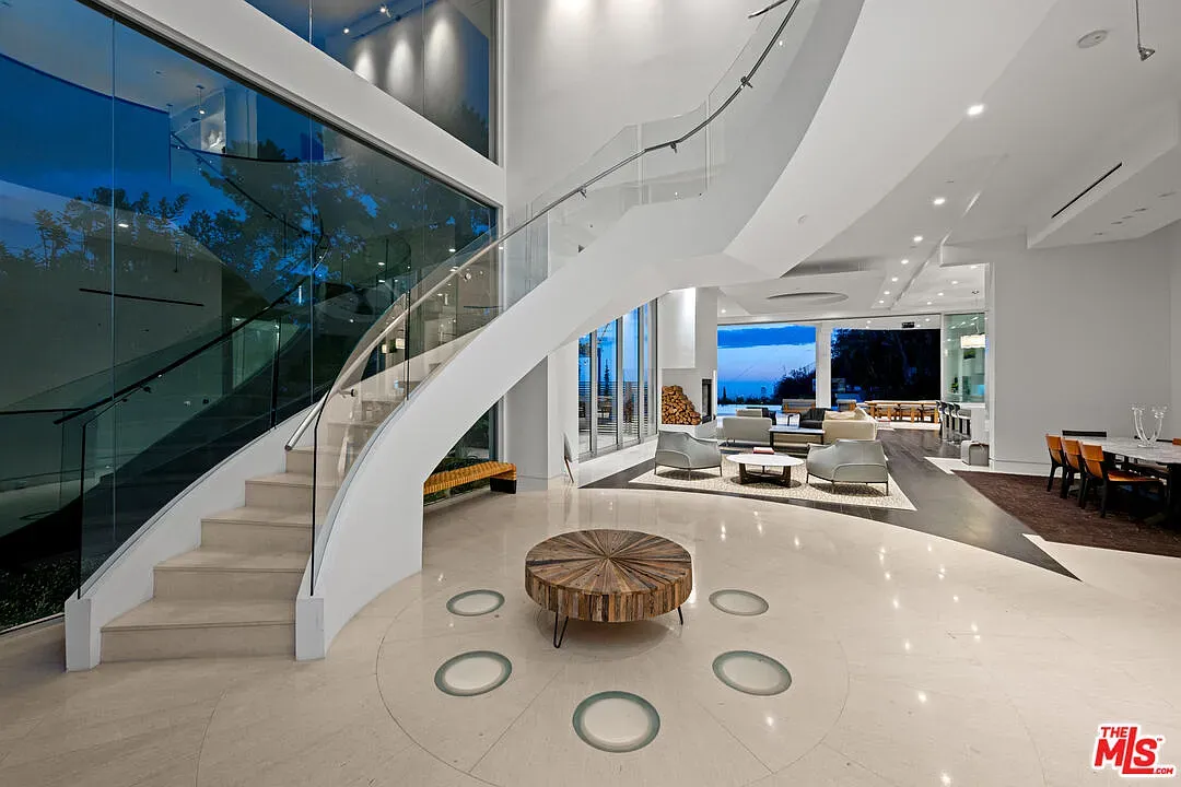 Spiral staircase moment. Glass railing, glossy floors, open two-story entry.