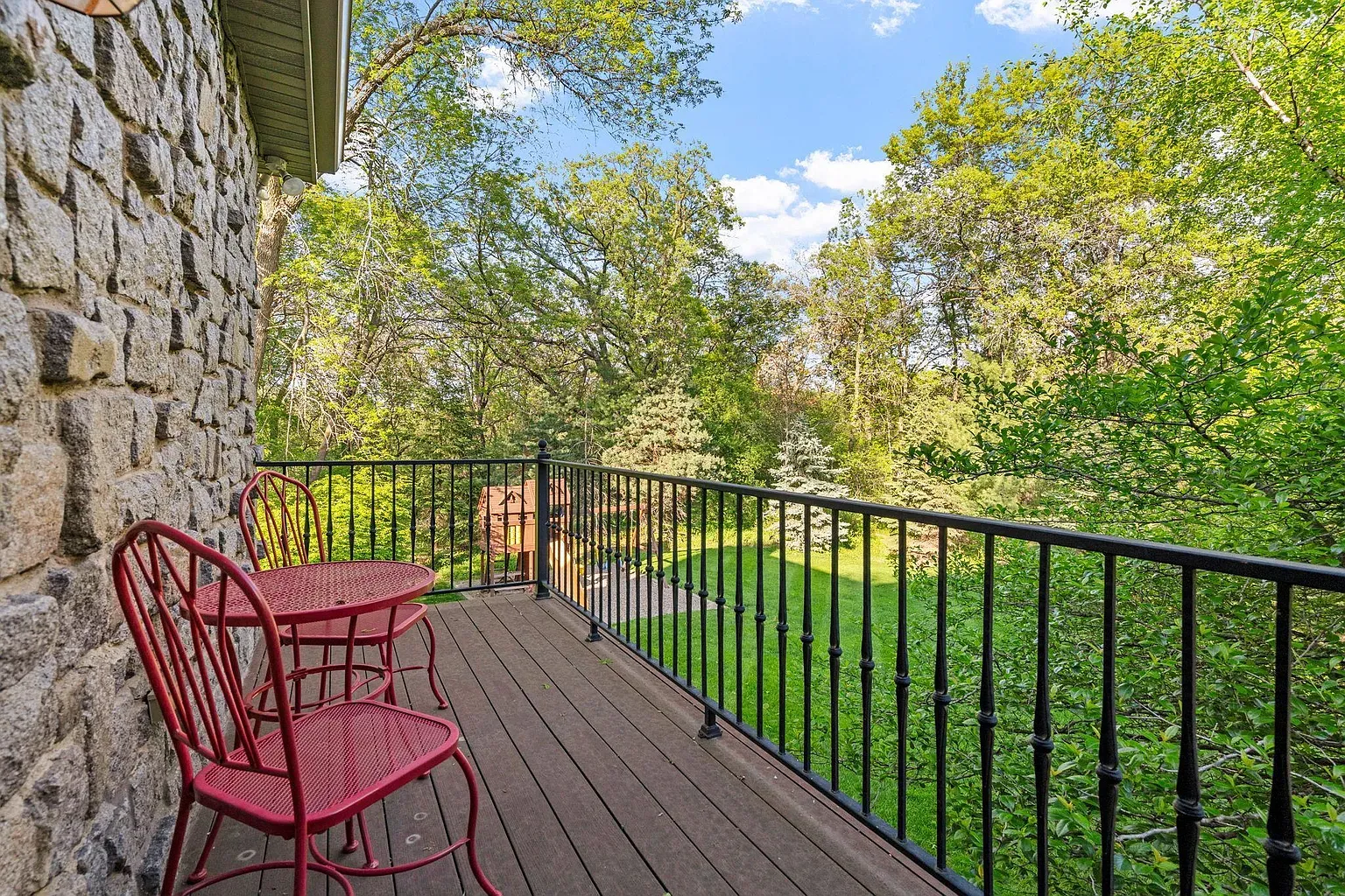 Little stone balcony with wood deck. Those two red chairs pop.