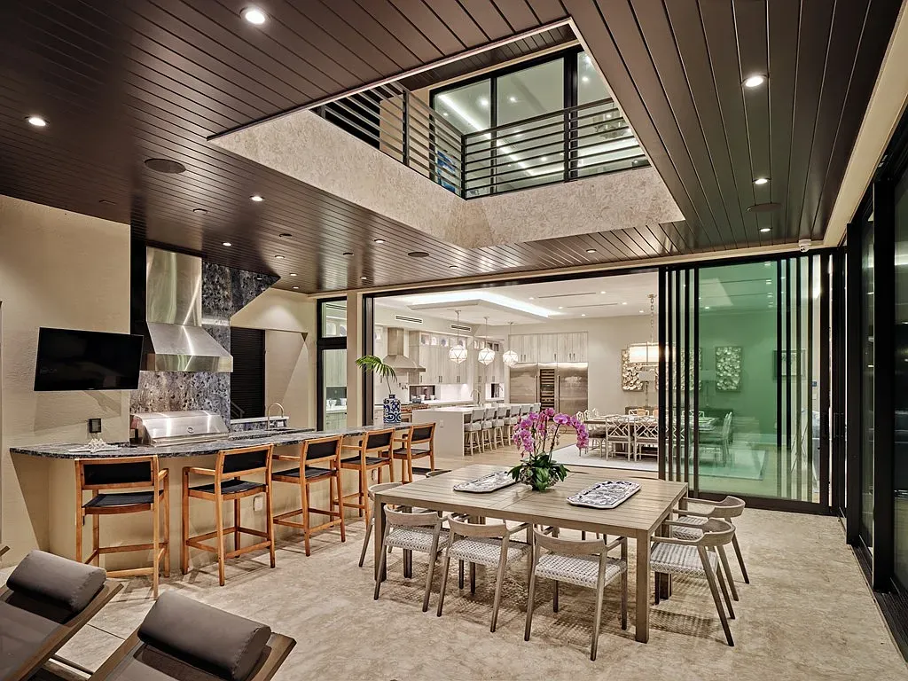 Open space with dark wood ceiling lines. Kitchen slides right into the patio.