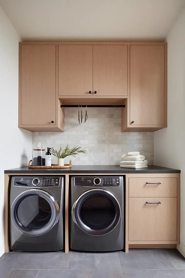 Graphite washer/dryer with wood cabinets. Laundry looks weirdly fancy.